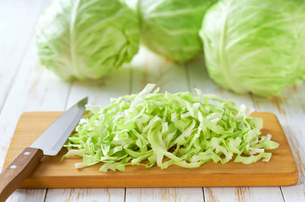 istock Whole and sliced fresh green cabbage on a cutting board, selective focus. 2168630675