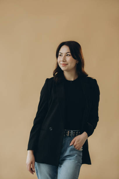 istock A stylish young brunette in a turtleneck and a jacket on a beige background. 2168634361