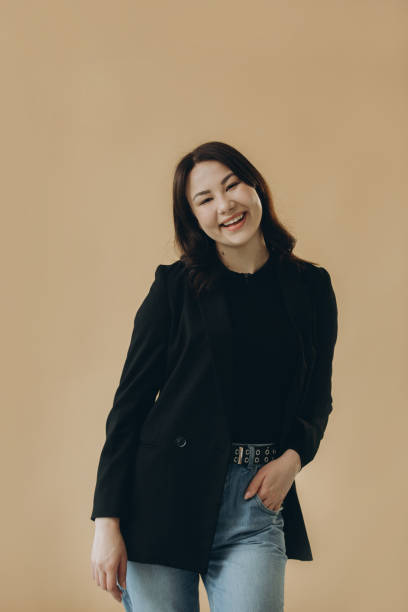 istock A stylish young brunette in a turtleneck and a jacket on a beige background. 2168634366