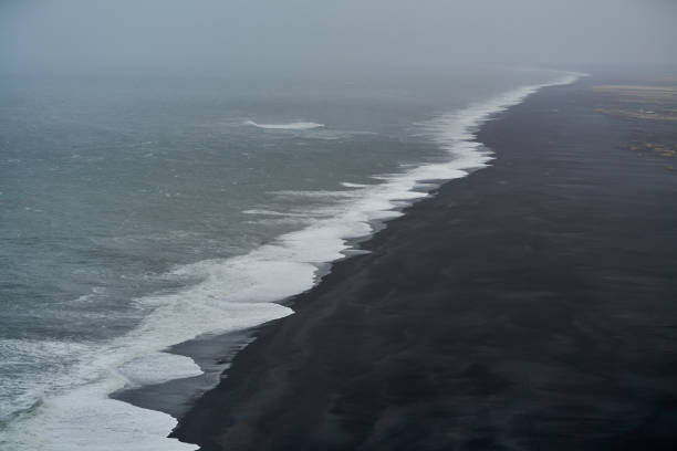 Powerful ocean waves crashing on a black sand beach on a stormy day