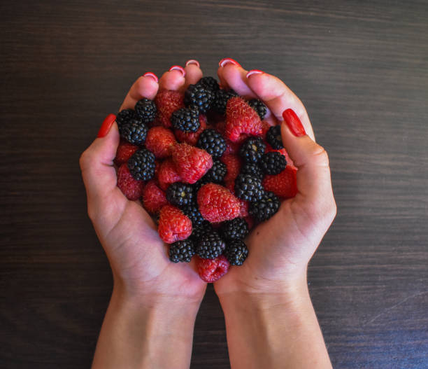 istock Raspberries and blackberries on the palm. They eat berries from the bush. Raspberry picking season. Picked by a farmer in the morning 2168639105