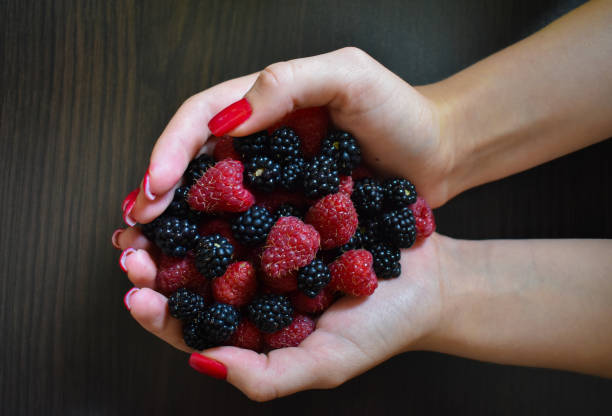 istock Raspberries and blackberries on the palm. They eat berries from the bush. Raspberry picking season. Picked by a farmer in the morning 2168639112