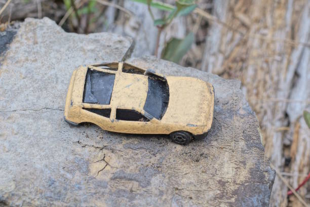 one small old metal brown black toy car lies on the gray table on the street