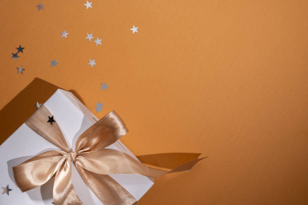 istock White box with gold bow and ribbons on color background. Gift box 2168641944