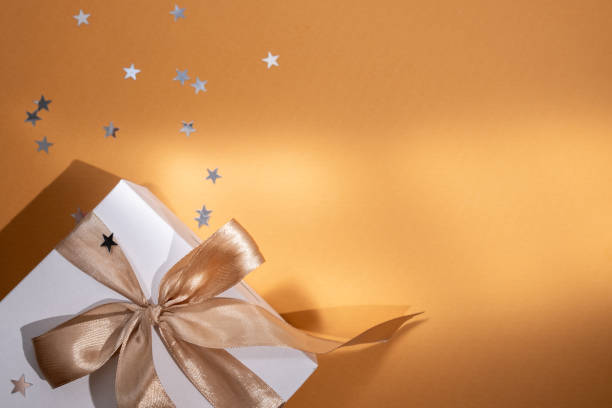 istock White box with gold bow and ribbons on color background. Gift box 2168641959