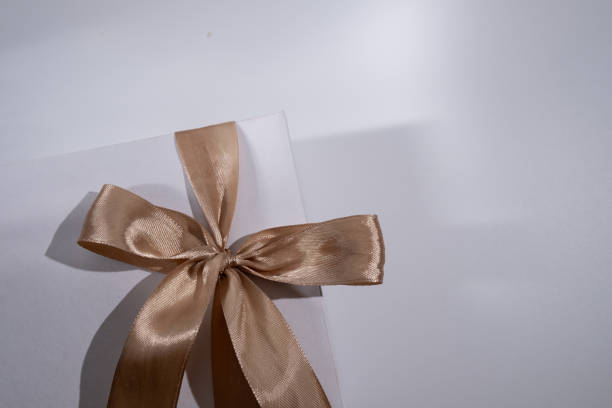 istock White box with gold bow and ribbons on color background. Gift box 2168641962