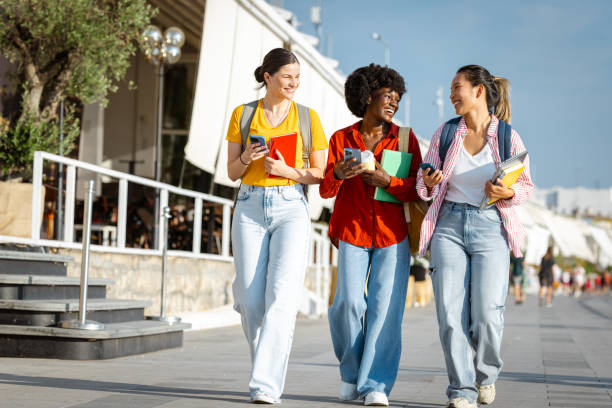 istock Female friends and students using smart phone and walking cheerfully after classes 2168642540