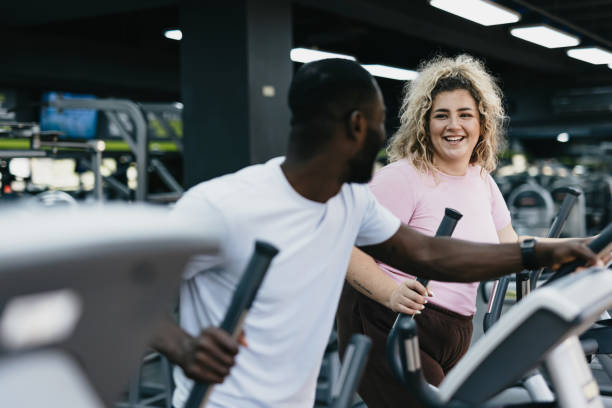 istock Happy gym workout: Woman and trainer using ellipticals. 2168645579