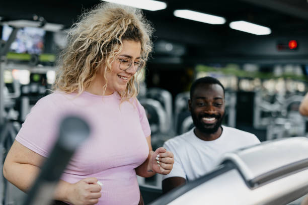 istock Smiling trainer and gym member on elliptical machine 2168645769