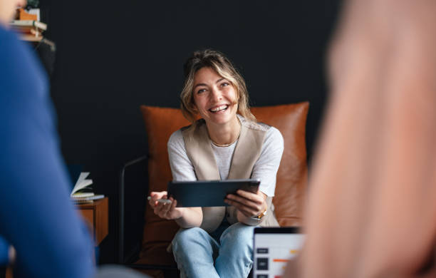 istock Smiling Woman Engaged in Team Discussion with Digital Tablet 2168660346