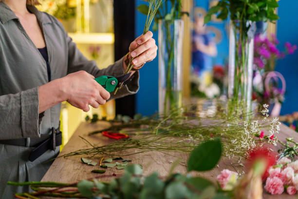 istock Female florist cutting flower branches while making flower arrangement 2168671604
