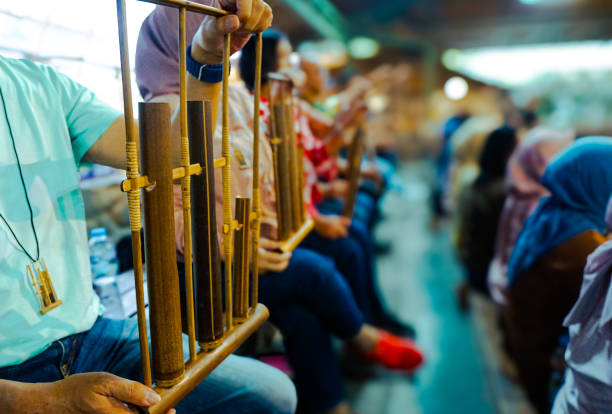 A man is playing angklung. That is a multi-tonal musical instrument that developed from the Sundanese people. Angklung is made of bamboo.