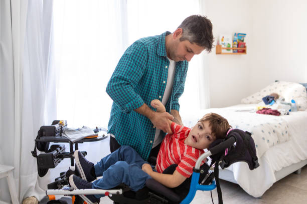 istock Beautiful boy with cerebral palsy  being changed by his father 2168684639