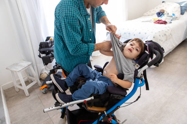 Beautiful boy with cerebral palsy  being changed by his father