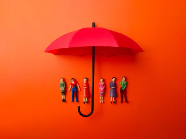 Miniature people women protected by red umbrella