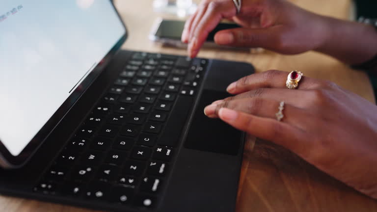 Close up to hands typing on a laptop tablet keyboard.