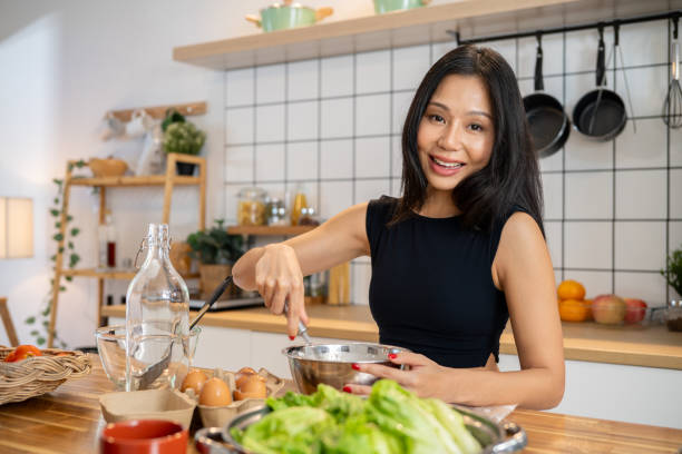 istock An Asian woman is whisking pancake mix in a bowl at the kitchen table while preparing breakfast. 2168694809