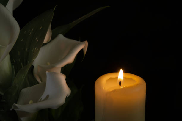 istock Burning wax candle and white calla lily flowers in darkness 2168703382