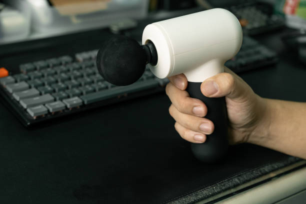 istock hand with a massage gun for therapeutic muscle relaxation. percussion massager. Copy space. 2168705387