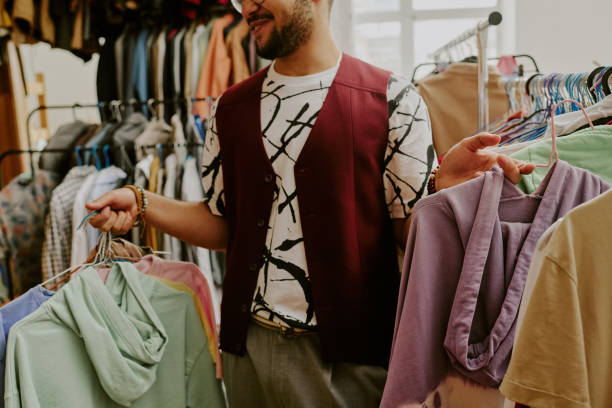 istock Smiling Man Browsing Clothes in Thrift Store Rack 2168705659