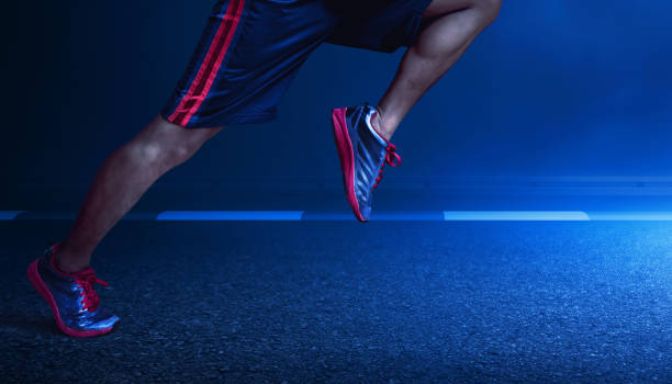 Young man runner legs sprinting at dark night with smoke