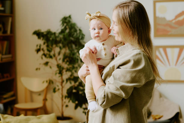 istock Holding Baby While Gazing at Indoor Plant 2168716617