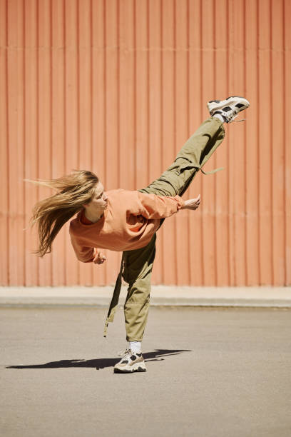 istock Young Woman Performing Dance Move Against Orange Wall 2168720064