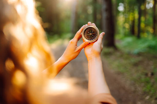 istock A hiker with curly hair holds a compass in their hands. 2168727818