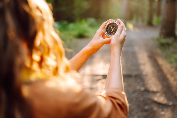 istock A hiker with curly hair holds a compass in their hands. 2168727824
