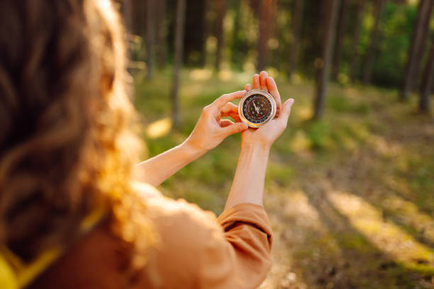istock A hiker with curly hair holds a compass in their hands. 2168727831