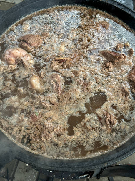 The meat is cooked in a cauldron over a fire