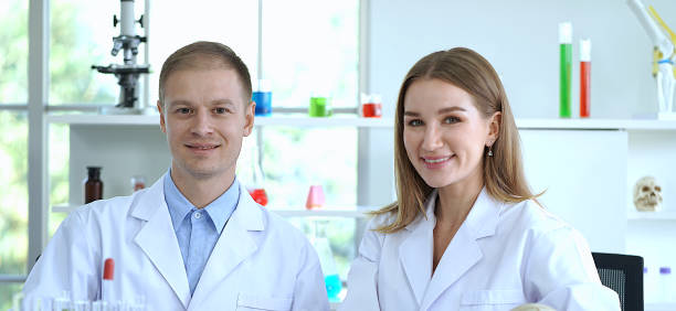istock Two smiling scientists in lab coats working in a laboratory. 2168737242