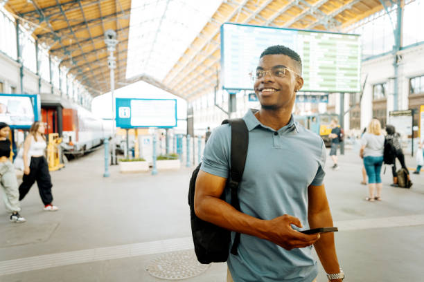 istock Millennial African American businessman going to work and using smart phone at the train station. Young businessman holding smart phone and smiling 2168741923