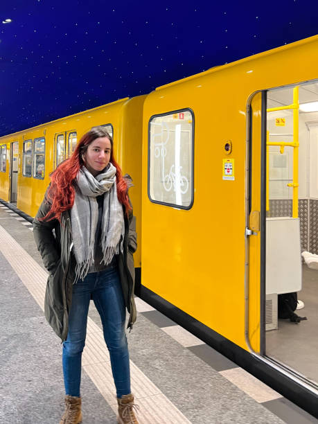 istock Beautiful young woman standing on subway platform by the yellow train 2168753636