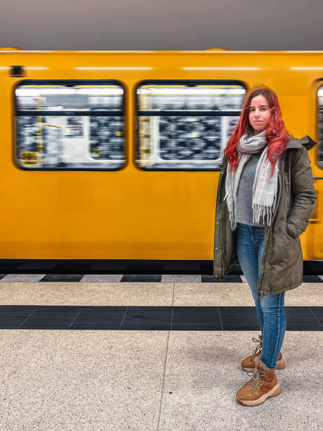 istock Beautiful young woman standing on subway platform, yellow train behind her 2168753665