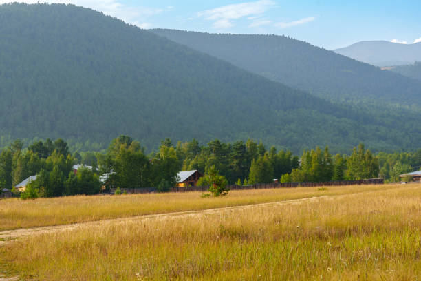istock Rural farmhouse in a sunlit field with mountain backdrop 2168756941