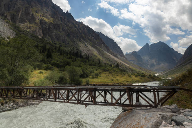 A small unsteady bridge over the rapid river in the mountains of Ala Archa National park valley