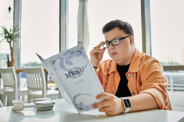 Young man with Down syndrome reading a menu in a lively cafe during afternoon hours