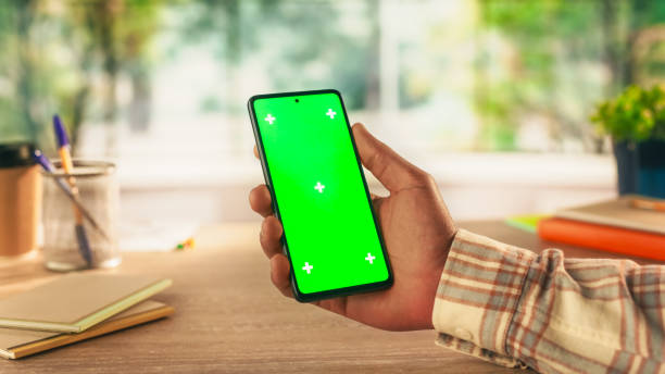 istock Anonymous Black Person Using a Smartphone with Mock Up Green Screen Chromakey Display with Motion Tracker Placeholders. Manager Browsing an App User Interface Online, Swiping and Tapping on the Phone 2168766285