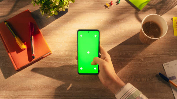 istock Business Manager Scrolling Through Apps on Smartphone with Green Screen Chromakey Mock Up Display in a Creative Workplace. Photo Template with Isolated Placeholder for Digital Marketing Demo 2168766405