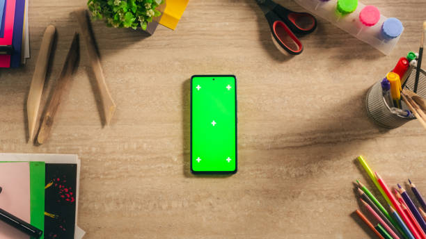 istock Top Down View of a Smartphone with Mock Up Green Screen Chromakey Display with Motion Tracker Placeholders. Cellphone Device on a Table with Designer Art Supplies and Tools. Social Media Promotion 2168766814