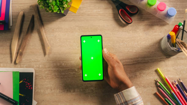 istock Art Student Holding a Modern Mobile Device in Front of a Camera. Computer with Green Screen Chroma Key Template for Digital Marketing, Promotion of Online Services, Design App, Internet Tutorials 2168766834