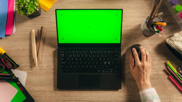 Top view of a wooden table with a laptop, mouse, and glasses