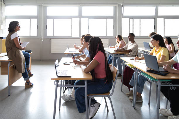 istock Female caucasian teacher explaining lesson to multiracial high school students 2168767194