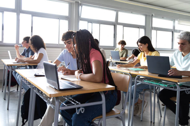 istock Group of multiracial teen high school student writing, doing homework, learning in class. 2168767198