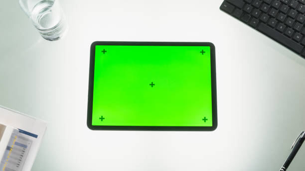 istock Top View of a Tablet Computer with Mock Up Green Screen Chromakey Display with Motion Trackers Standing on an Office Desk Next to Keyboard, Black Pen, Documents and a Glass of Water 2168768268