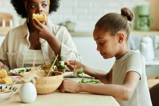 istock Black Girl Eating Green Salad at Kitchen Table 2168777462