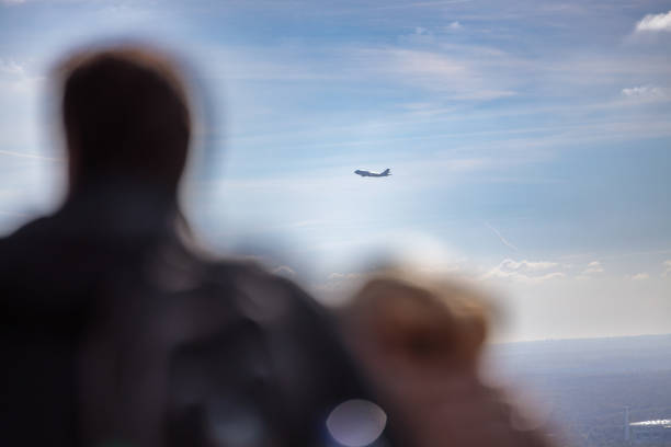Airplane flying in the distance in the sky above Frankfurt am Main, people in foreground defocused