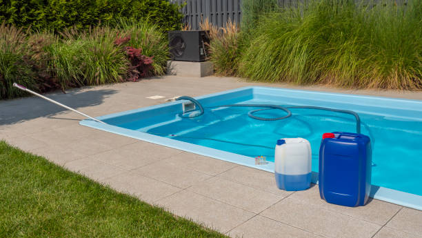 istock A well-maintained poolside scene with chemical containers, a floating cleaning hose in the pool, and a water testing kit, emphasizing essential pool care. 2168778965