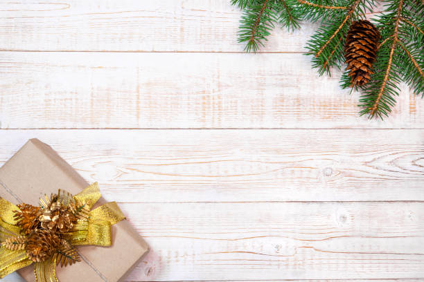 istock Christmas background - fir branches with cones and gift box on a white wood table. Flat layout, top view composition border with copy space 2168787380